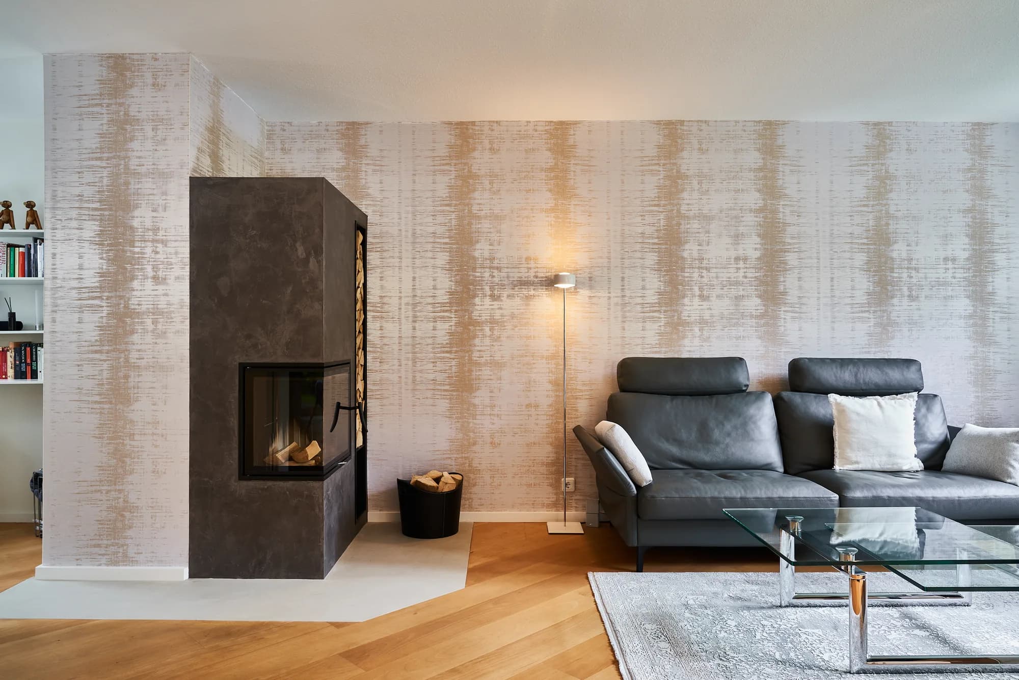 Anthrazitfarbene Kaminanlage in einem Wohnzimmer mit grauem Ledersofa