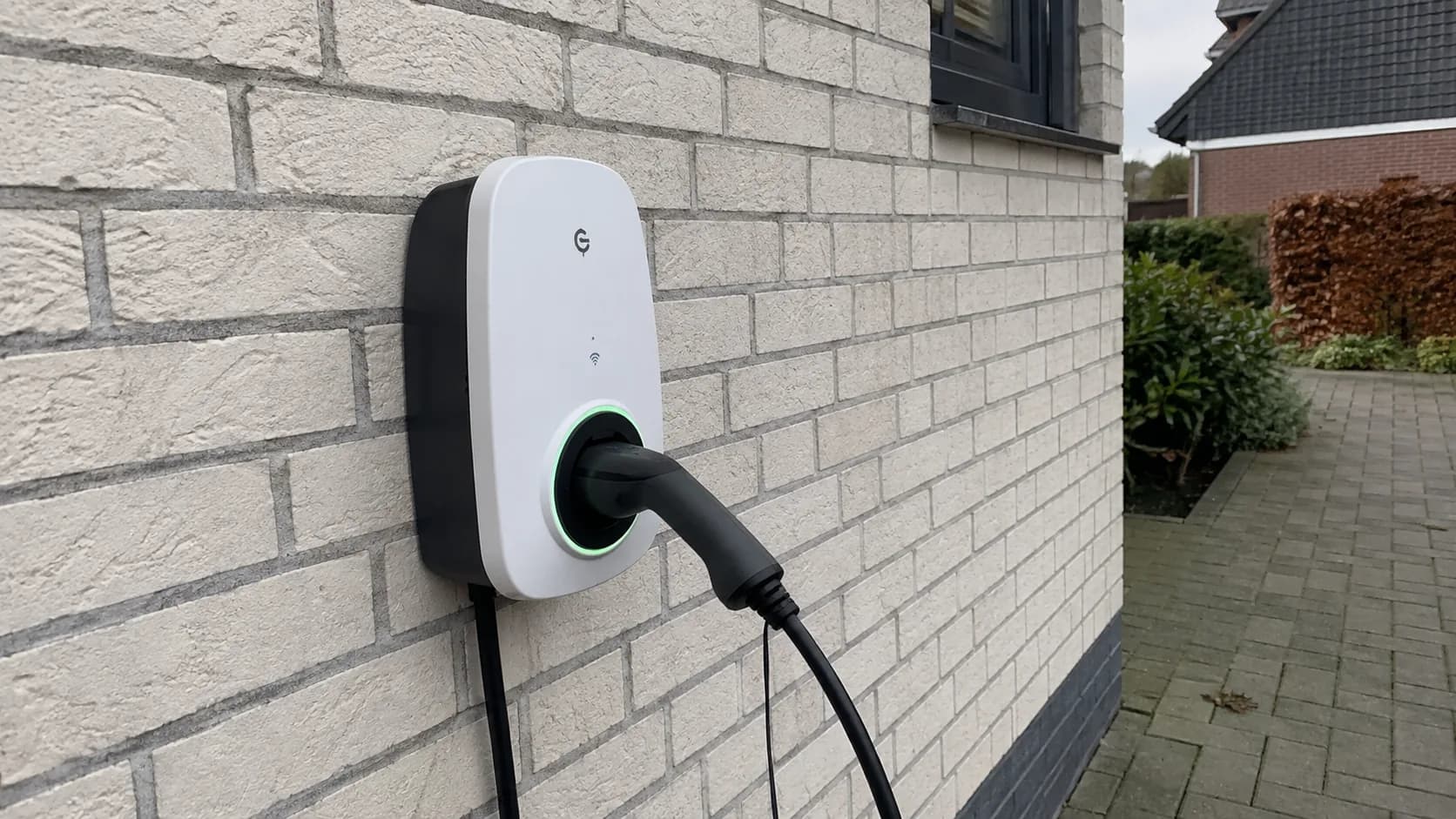 Wallbox an einer Hauswand mit ladendem Elektrofahrzeug