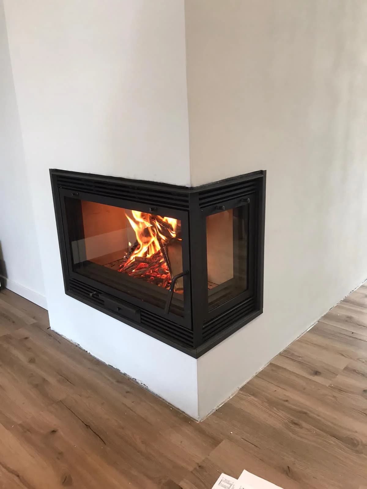 Fertig eingebaute Eck-Heizkassette mit brennendem Feuer im selben Raum