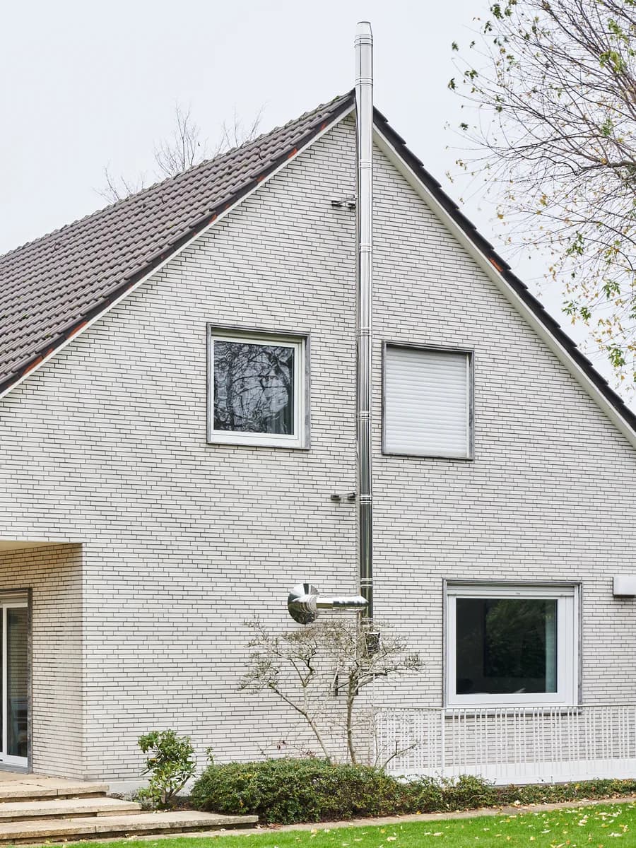 Doppelwandiger Edelstahlschornstein an der Giebelseite eines Einfamilienhauses, über den First geführt