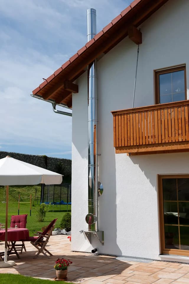 Doppelwandiger Edelstahlschornstein an der Fassade eines Wohnhauses