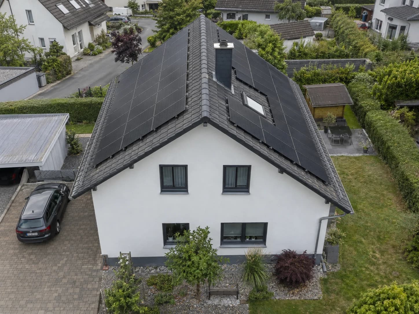 Drohnenaufnahme eines Einfamilienhauses mit Solarmodulen auf beiden Dachseiten
